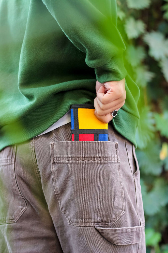 crafted from durable cotton canvas and influenced by Piet Mondrian's Colorblock art. The wallet showcases a captivating arrangement of geometric shapes and contrasting hues, offering a contemporary and eye-catching design.