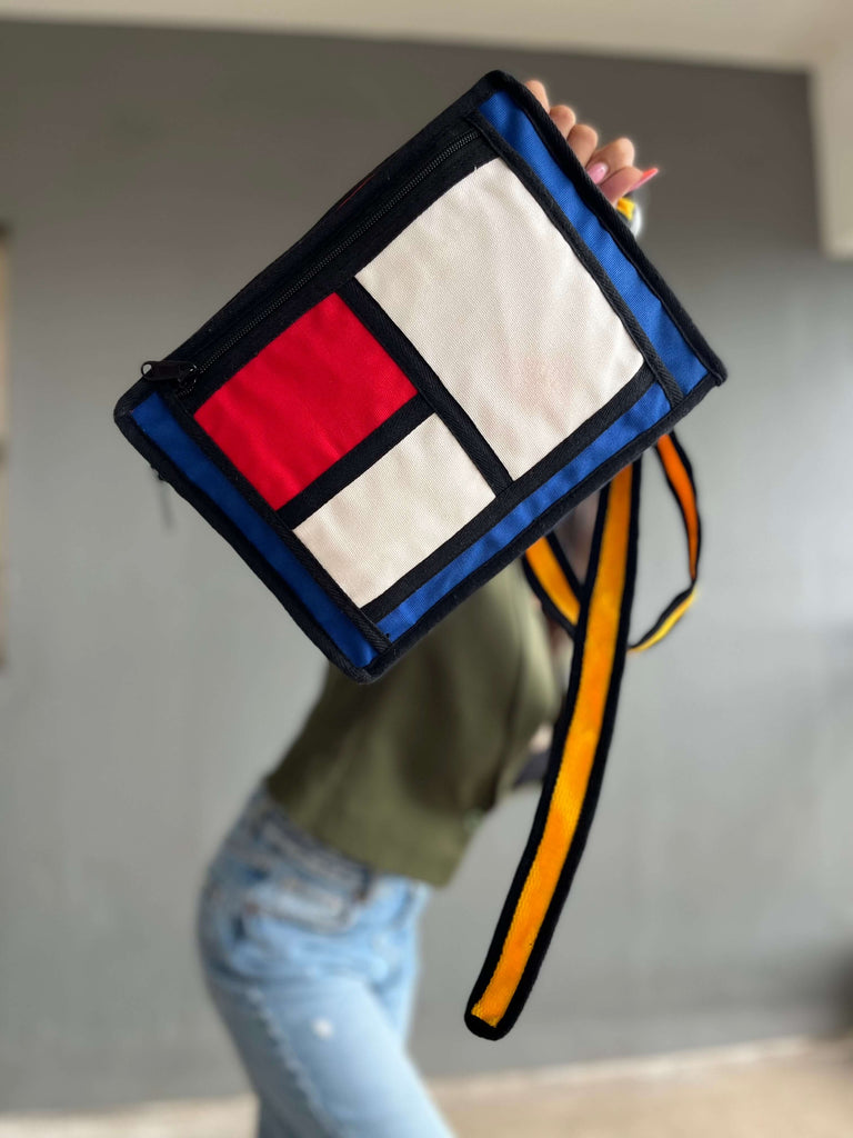 a stylish accessory made of cotton canvas, inspired by Piet Mondrian's Colorblock art. The bag features bold geometric patterns in primary colors, adding a touch of artistic flair to your ensemble